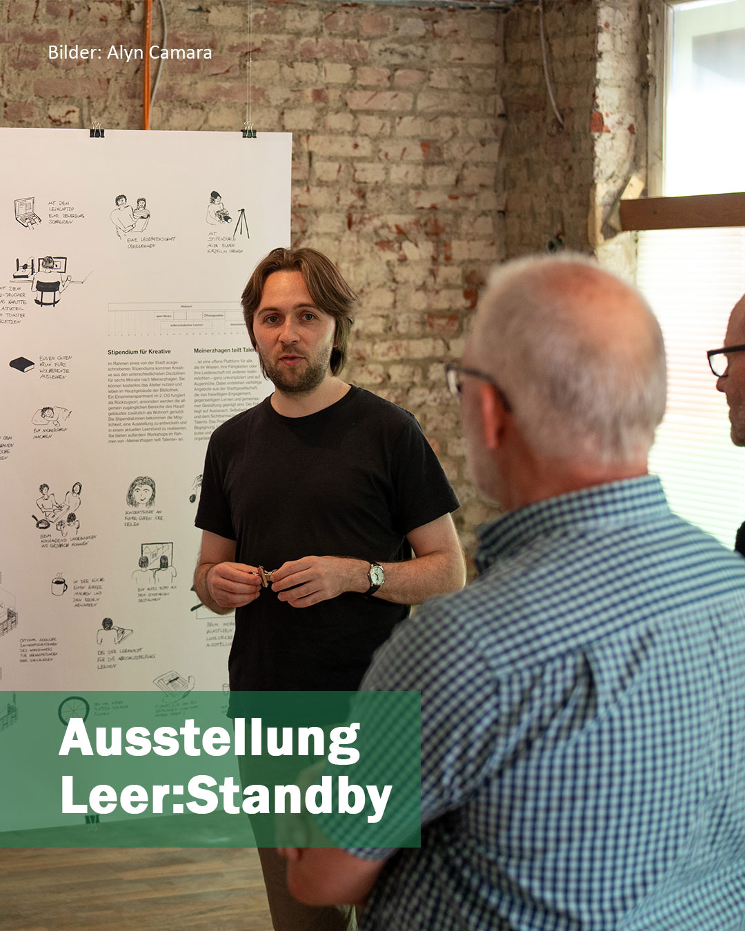 Person vor Exponat (Plakat) mit Zuschauern